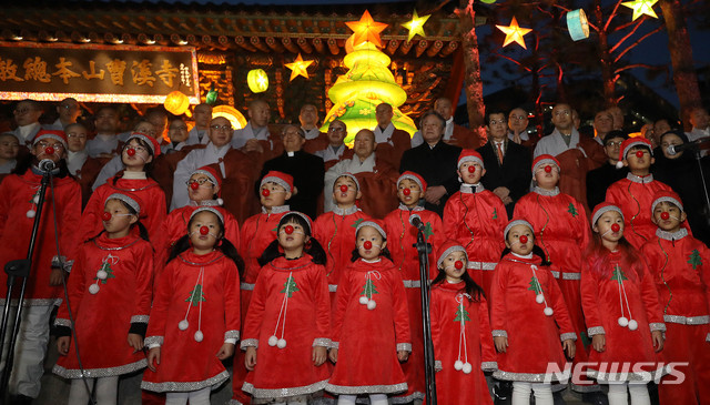 【서울=뉴시스】추상철 기자 = 조계사 '성탄 크리스마스 트리' 점등식이 열린 19일 오후 서울 종로구 조계사 일주문 앞에서 어린이 합창단이 점등된 트리와 함께 캐롤을 부르고 있다. 2018.12.19. scchoo@newsis.com