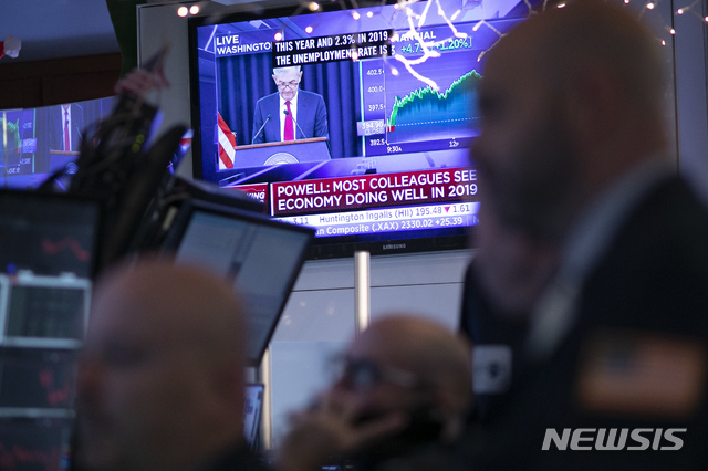 Traders at the New York Stock Exchange listen as Federal Reserve Chair Jerome Powell is seen on a video screen giving a news conference from Washington after the Fed announced a rate increase, Wednesday, Dec. 19, 2018. (AP Photo/Mark Lennihan)