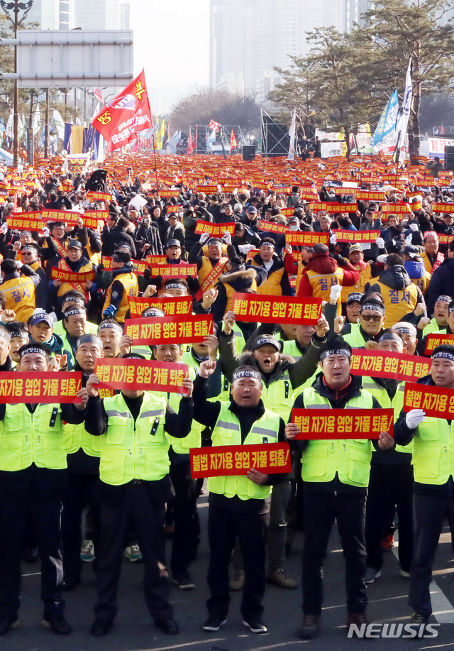 【서울=뉴시스】조성봉 기자 = 20일 오후 서울 영등포구 여의도 국회 인근에서 열린  '카카오 카풀 반대' 제3차 택시 생존권 사수 결의대회에서 참가자들이 ‘불법자가용 영업 카풀 퇴출' 손피켓을 들고 구호를 외치고 있다. 2018.12.20.suncho21@newsis.com