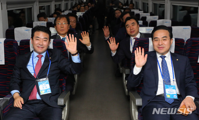 【서울=뉴시스】배훈식 기자 = 남북 동서해선 철도, 도로 연결 및 현대화 착공식에 참석하는 더불어민주당 박정(왼쪽부터), 윤후덕, 송영길, 윤관석, 박홍근 의원이 26일 오전 서울 용산구 서울역에서 출발, 판문역에 도착하는 열차 안에서 손을 흔들고 있다. 2018.12.26 dahora83@newsis.com
