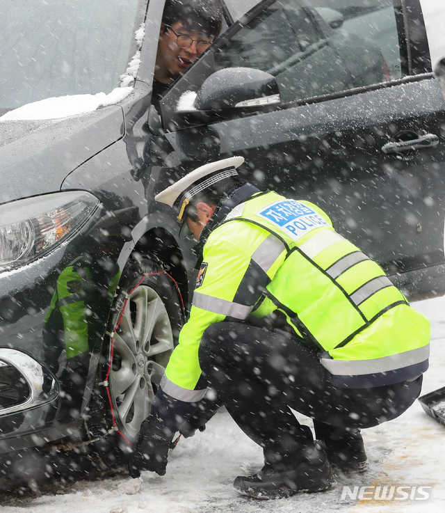 【제주=뉴시스】우장호 기자 = 제주 산간에 대설주의보가 발효 중인 28일 오전 제주시 어승생 교통안내센터 앞에서 자치경찰이 월동장구 착용을 돕고 있다. 기상청에 따르면 29일 새벽까지 제주 산간에는 최고 20㎝가 넘는 많은 눈이 내릴 것으로 예보됐다. 2018.12.28. woo1223@newsis.com