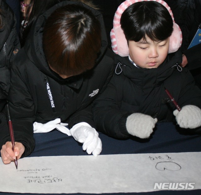 【춘천=뉴시스】박종우 기자 = 2018년 12월31일에서 2019년 1월1일로 넘어가는 오전0시, 강원 춘천시 춘천시청 앞 광장에서 해넘이·해맞이 행사가 열린 가운데 행사에 참여한 아이들이 새해 소원을 쓰고 있다. 2019.01.01.&nbsp; jongwoo425@newsis.com