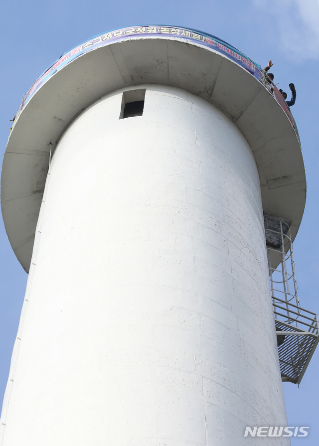 【서울=뉴시스】이윤청 수습기자 = 홍기탁 파인텍지회 전 지회장, 박준호 사무장이 지난 1일 오전 서울 양천구 서울에너지공사 목동열병합발전소 굴뚝 농성장에서 손을 흔들고 있다. 2019.01.01. radiohead@newsis.com