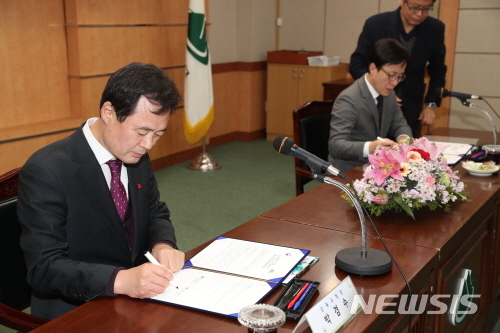 【서울=뉴시스】강북구-통일교육원 업무협약식에서 협약서에 서명하는 박겸수 강북구청장(좌). 2019.01.03. (사진=강북구 제공)