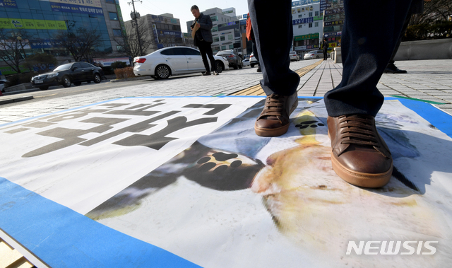 【광주=뉴시스】신대희 기자 = 사자명예훼손 혐의를 받고 있는 전두환씨의 형사재판이 열리는 7일 오후 광주지법 입구쪽에서 한 시민이 전씨 현수막을 밟고 지나가고 있다. 2019.01.07.  sdhdream@newsis.com