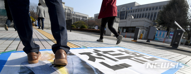 【광주=뉴시스】신대희 기자 = 사자명예훼손 혐의를 받고 있는 전두환씨의 형사재판이 열리는 7일 오후 광주지법 입구쪽에서 한 시민이 전씨 현수막을 밟고 지나가고 있다. 2019.01.07.  sdhdream@newsis.com