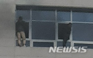 【천안=뉴시스】함형서 기자 = 14일 오후 4시 56분께 충남 천안시 서북구 쌍용동의 다중이용시설인 라마다앙코르 호텔에서 불이난 가운데 시민 2명이 창문 밖 난간을 밟고 구조대원을 기다리고 있다. 2019.01.14.(사진=독자 제공)photo@newsis.com