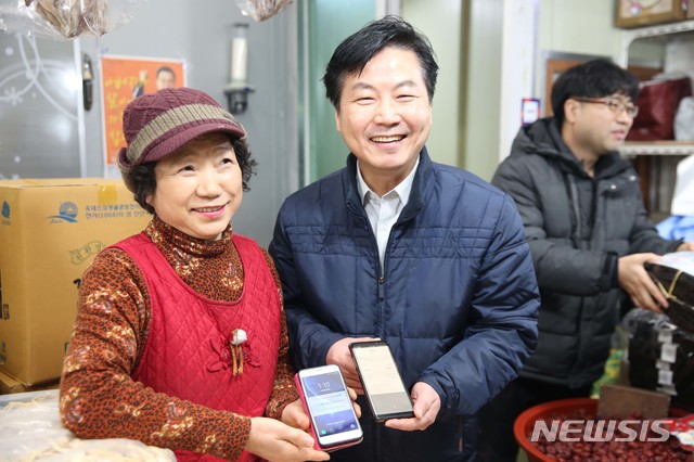 【서울=뉴시스】중소벤처기업부 홍종학 장관이 25일 전남 목포자유시장을 방문해 제로페이로 물품을 구입하고 있다. 2019.01.25. (사진=중소벤처기업부 제공)&nbsp; photo@newsis.com