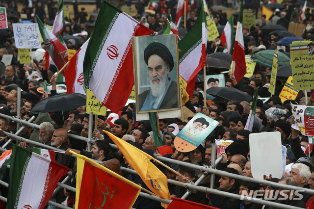 【테헤란=AP/뉴시스】11일(현지시간) 이란 수도 테헤란의 자유 광장에서 이슬람혁명 제40주년 기념 행사가 열려 이란 국민들이 국기와 혁명 지도자였던 아야톨라 루훌라 호메이니의 초상화를 들고 행사에 참여하고 있다. 이슬람 혁명은 1979년 2월11일 팔레비왕조를 무너뜨리고 이슬람원리주의에 입각한 이란이슬람공화국을 탄생시킨 혁명이다. 2019.02.11.