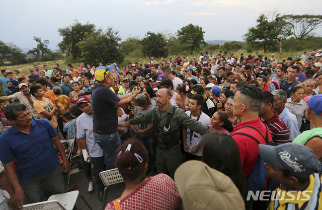 【우레나=AP/뉴시스】11일(현지시간) 베네수엘라의 한 공무원이 우레나 외곽 티엔디타스 다리 부근에서 마두로 정권이 준비한 구호 물품을 배분하기 전에 모여든 군중을 진정시키고 있다. 트럼프 행정부가 베네수엘라 내 반 마두로 세력을 지지한 지 근 3주가 지나면서 궁지에 몰린 마두로는 자신의 권력 양도가 임박했다는 예측을 애써 부인하고 있다. 2019.02.12.