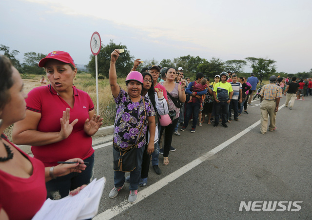 【우레나=AP/뉴시스】11일(현지시간) 베네수엘라 국민들이 우레나 외곽 티엔디타스 다리 부근에서 마두로 정권이 준비한 구호 물품 꾸러미를 받기 위해 줄지어 서 있다. 줄선 국민들이 티켓을 들어 보이고 있다. 트럼프 행정부가 베네수엘라 내 반 마두로 세력을 지지한 지 근 3주가 지나면서 궁지에 몰린 마두로는 자신의 권력 양도가 임박했다는 예측을 애써 부인하고 있다. 2019.02.12.