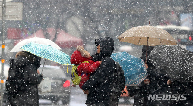 [서울=뉴시스]추상철 기자 =지난해 2월 19일 오전 눈이 내린 서울 종로구 세종문화회관 앞에서 출근길 시민이 아이를 안고 발걸음을 재촉하고 있다. 2019.02.19.&nbsp; scchoo@newsis.com