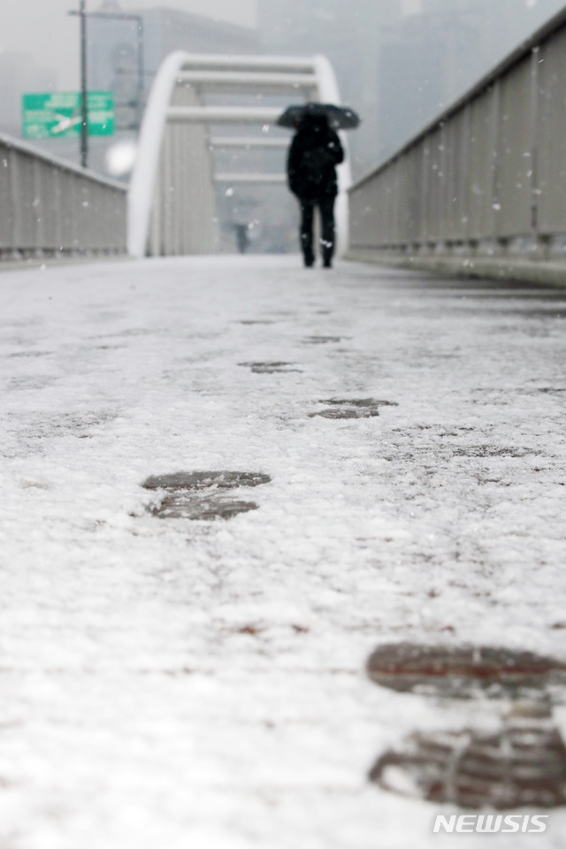 【서울=뉴시스】박미소 수습기자 = 눈이 내리는 지난 19일 오전 서울 영등포구 인근 다리 위에 한 시민이 걷는 대로 발자국이 남겨지고 있다. 2019.02.19. misocamera@newsis.com