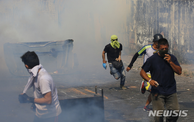 Demonstrators run away from a cloud of tear gas during clashes with the Bolivarian National Guard in Urena, Venezuela, near the border with Colombia, Saturday, Feb. 23, 2019. Venezuela's National Guard fired tear gas on residents clearing a barricaded border bridge between Venezuela and Colombia on Saturday, heightening tensions over blocked humanitarian aid that opposition leader Juan Guaido has vowed to bring into the country over objections from President Nicolas Maduro. (AP Photo/Fernando Llano)