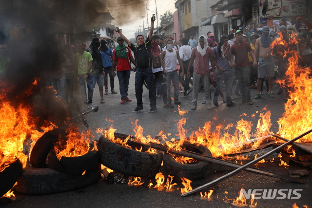  【우레나=AP/뉴시스】23일(현지시간)베네수엘라 우레나에서 시민과 군이 충돌한 가운데 시위대가 쌓아 놓은 장애물에 불을 질러 벽을 만들고 시위를 벌이고 있다.&nbsp; 이날 새벽 콜롬비아 접경지역인 베네수엘라 우레나에서는 구호 물품을 반입하려는 야당 인사들과 자원봉사자, 시민들이 이를 저지하는 군과 충돌했다.&nbsp; 베네수엘라 국경수비대는 우레나의 국경 다리에서 구호물자 수송을 위한 트럭의 통행을 위해 바리케이드를 치우려는 시민들에게 최루탄을 쏘아댔다. 베네수엘라의 임시 대통령을 자임한 후안 과이도 국회의장은 이날을 인도주의 구호 물품 반입일로 선언한 바 있다. 2019.02.24. 
