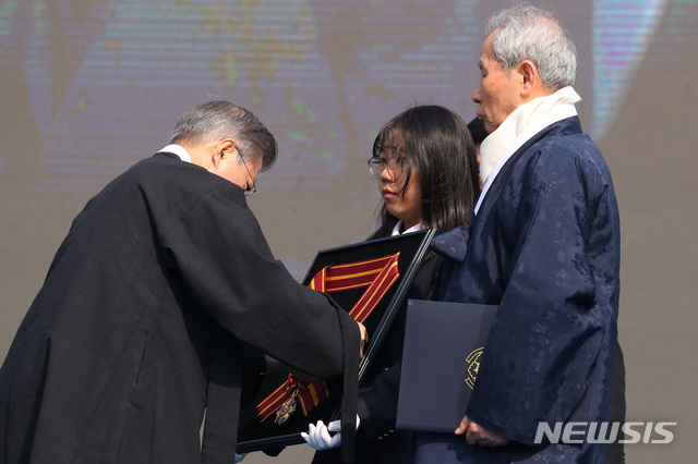 【서울=뉴시스】전신 기자 = 문재인 대통령이 1일 서울 광화문광장에서 열린 제100주년 3.1절 기념식에서 고 유관순 열사에 대한 건국훈장 대한민국장 훈장을 이화학당 100년 후배인 이화여고 2학년 윤수진 학생이 들고있는 추서판에 달아주고 있다. 2019.03.01. photo1006@newsis.com