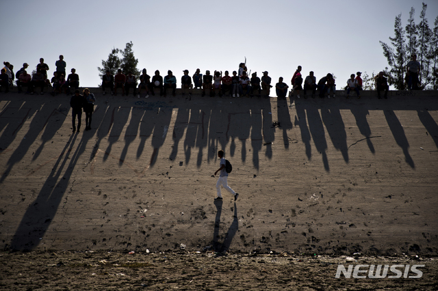 【티후아나( 멕시코)=AP/뉴시스】 지난 해 11월 멕시코 국경의 티후아나에서 건너다 보이는 차파랄 국경통로에서 이를 봉쇄하고 있는 미국 국경경비대와 대치 중인 이민자들. 미국 현지 TV방송들은 미 국토안보부가 이민들을 막기 위해 국경 세관에서 언론인과 미국 시민들까지 세밀하게 조사를 하고 있다고 보도했다.