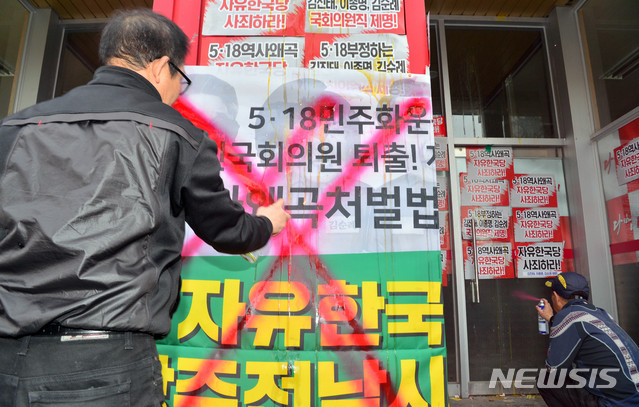 【광주=뉴시스】변재훈 기자 = 9일 오후 광주 북구 중흥동 자유한국당 광주시·전남도당사 앞에서 '한국당 규탄 시·도민대회'를 열린 가운데 대회 참가자들이 5·18 망언 의원들의 얼굴이 담긴 현수막에 페인트칠을 하는 퍼포먼스를 벌이고 있다. 2019.03.09. wisdom21@newsis.com