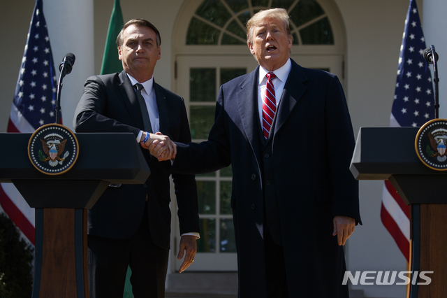 【워싱턴=AP/뉴시스】도널드 트럼프(오른쪽) 미국 대통령과 자이르 보우소나루 브라질 대통령이 19일(현지시간) 백악관에서의 정상회담을 마치고 열린 공동기자회견에서 악수하고 있다. 두 정상은 공동기자회견에서 "양국은 베네수엘라의 니콜라스 마두로 독재 정권을 끝내기 위해 가능한 모든 것을 할 것"이라며 공조의 뜻을 밝혔다.'브라질의 트럼프', '남미의 트럼프'라는 별명의 보우소나루 대통령은 취임 이후 첫 양자 외교로 미국을 공식 방문했다. 2019.03.20.
