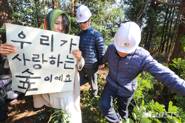 【제주=뉴시스】우장호 기자 = 23일 오전 환경단체 반대와 경관 훼손 논란 등으로 중단됐던 제주시 구좌읍 비자림로 확장공사가 7개월만에 재개된 가운데 시민 활동가가 벌목 작업을 반대하며 현장 관계자들과 맞서고 있다. 2019.03.23. woo1223@newsis.com