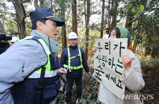 【제주=뉴시스】우장호 기자 = 23일 오전 환경단체 반대와 경관 훼손 논란 등으로 중단됐던 제주시 구좌읍 비자림로 확장공사가 7개월만에 재개된 가운데 시민 활동가가 벌목 작업을 반대하며 경찰과 맞서고 있다. 2019.03.23. woo1223@newsis.com