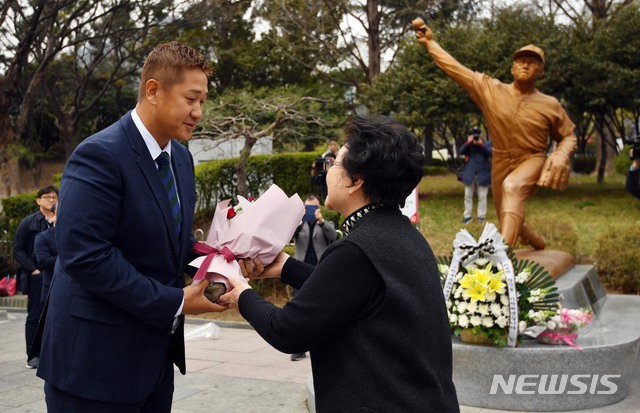 【부산=뉴시스】 하경민 기자 = 한국프로야구선수협회장에 선출된 롯데 자이언츠 이대호(37) 선수가 25일 부산 동래구 사직야구장에서 취임 기자회견을 갖기에 앞서 고 최동원 선수 동상에 헌화한 이후 최동원 선수의 어머니인 김정자 여사로부터 축하 꽃다발을 받고 있다. 2019.03.25. yulnetphoto@newsis.com