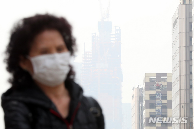 【서울=뉴시스】이윤청 수습기자 = 수도권 지역의 미세먼지 농도가 '나쁨' 수준을 보인 27일 서울 마포구 공덕역 인근에서 바라본 여의도 일대 하늘이 뿌연 가운데 시민들이 마스크를 쓰고 걷고 있다. 2019.03.27.&nbsp; radiohead@newsis.com