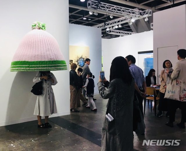 【홍콩=뉴시스】 박현주 미술전문기자 = 홍콩 아트바젤기간 관람객들에게 행복 바이러스를 전한 리만 머핀부스에 설치된 에르빈 부름의 분홍색 털모자. 실로 짠 거대한 털모자는 보는 순간 관람객들의 머리를 집어넣게 하는 마력을 과시하며 개관 3일만에 한화 약 1억선에 팔렸다.