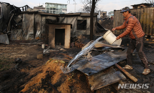 【속초=뉴시스】김경목 기자 = 5일 오후 산불 피해가 큰 강원 속초시 장사동 장천마을의 주민이 볍씨에 붙은 불을 끄려고 물을 붓고 있다. 2019.04.05. photo31@newsis.com