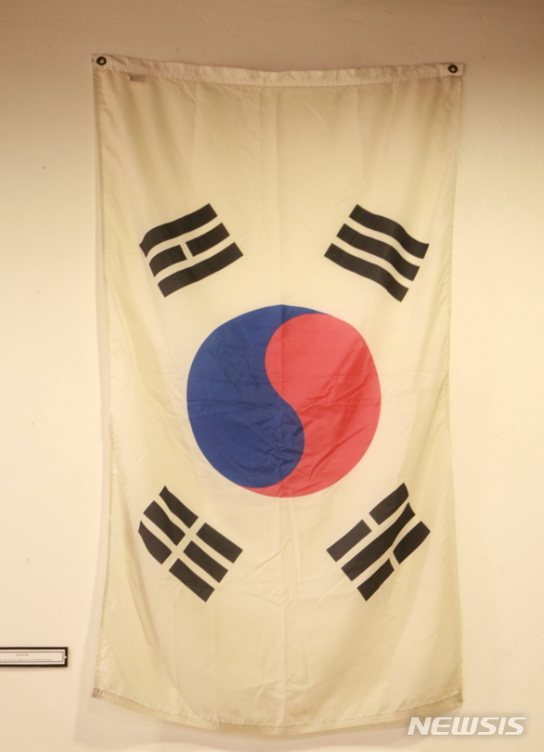 【서울=뉴시스】 김태겸 기자 = 지난 2월 12일, 상해 임시정부 100주년 취재차 갔던 미 서부 중가주 다뉴바시에서 만난 한인역사연구회 차만자 박사(캘리포니아 주립대 정치학과 명예교수)가 한인 이주노동자들의 기록물이 전시돼 있는 투라레카운티 박물관(Tulare County Museum)에서 당시 한인들이 사용했던 태극기를 보여주고 있다.&nbsp; 1903년 구한말 갤릭호에 올라 하와이를 거쳐 미국 본토로 온 한인 이주 노동자들은 노예처럼 일해서 번 일당 5센트 가운데 상당액을 독립운동자금으로 기꺼이 내놓아 상해임시정부 재정에 크게 기여했지만 고국에 돌아오지 못하고 이역만리에서 제대로된 묘비명도 없이 쓸쓸하게 최후를 맞이했다. 1903~1905년 사이 고종은 수민원(綏民院. immigration office)이라는 이민귀화국을 신설하고 한인 노동자 약 7200여명을 미국 하와이 사탕수수 농장으로 집단 이주 시켰다. 이 중 약 2000여명은 노동기간을 마치고 미국 본토인 샌프란시스코로 향한다. 그 중 일부는 탄광이나 은광으로 일부는 미 서부 중가주 리들리 다뉴바 과일 농장으로 향한다. 이들이 바로 상해 임시정부의 수립 자금의 60%를 낸 500여명의 민초 독립운동가들이다. 2019.04.10.&nbsp; patk21@newsis.com 