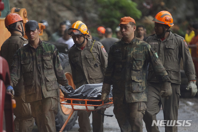 【리우데자네이루= AP/뉴시스】 브라질 리우 시의 갑작스러운 폭우와 진흙 산사태로 9일 숨진 희생자들의 시신을 소방구조대와 군 지원병들이 함께 운구하고 있다.  