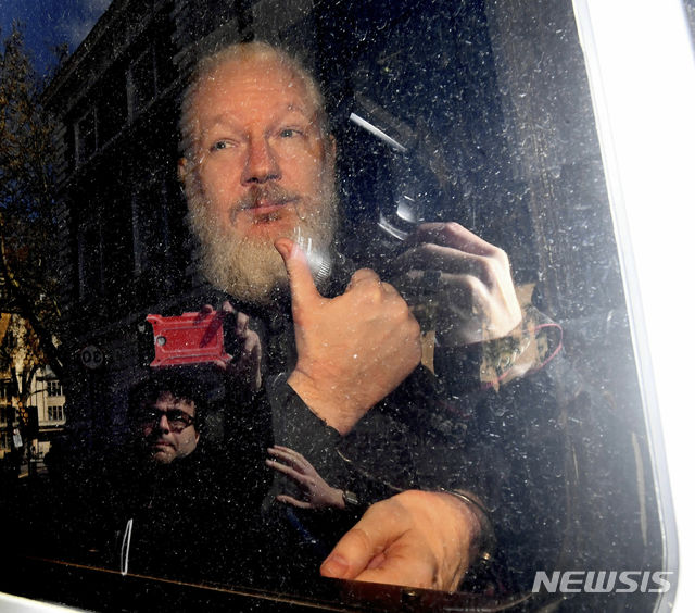  【런던=AP/뉴시스】 위키리크스 창시자 줄리언 어산지가 11일 런던 경찰에 의해 망명 은신중이던 에콰도르 대사관에서 체포되어 끌려나온 뒤 범죄인부 절차 상 치안 법정으로 호송되고 있다. 어산지가 차 안에서 취재진에게 엄지를 쳐들어 보이는 제스처를 했으며 법정에서 판사에게 보석조건 위반 등 혐의에 무죄를 주장했다. 2019. 4. 11.&nbsp;&nbsp; 