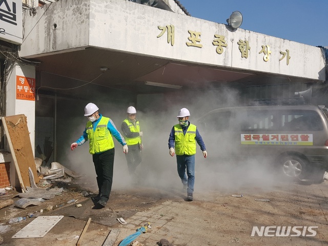 【서울=뉴시스】김온유 기자=12일 서울 강남구 개포주공1단지에서 명도 강제집행을 시도하던 집행관들이 전국철거민연합회(전철연) 관계자들이 뿌린 소화기 분진을 피해 건물을 나오고 있다.2019.04.12