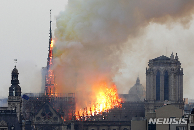 Flames rise from Notre Dame cathedral as it burns in Paris, Monday, April 15, 2019. Massive plumes of yellow brown smoke is filling the air above Notre Dame Cathedral and ash is falling on tourists and others around the island that marks the center of Paris. (AP Photo/Thibault Camus)