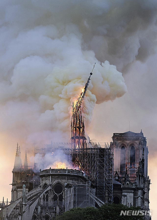 【파리=AP/뉴시스】프랑스 파리의 랜드마크인 노트르담 대성당의 중앙 첨탑이 15일(현지시간) 불길에 휩싸인채 옆으로 기울어지며 무너지고 있다. 2019.04.16