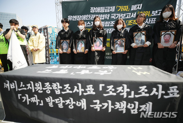 【서울=뉴시스】박미소 수습기자 = 박경석 전국장애인야학협의회 이사장이 19일 오후 서울 종로구 정부서울청사 앞에서 '2019 420장애인차별철폐 1박 2일 전국집중투쟁'의 일환으로 열린 장애등급제 가짜 폐지 장례식에서 입관식을 진행하고 있다. 2019.04.19.&nbsp; misocamera@newsis.com