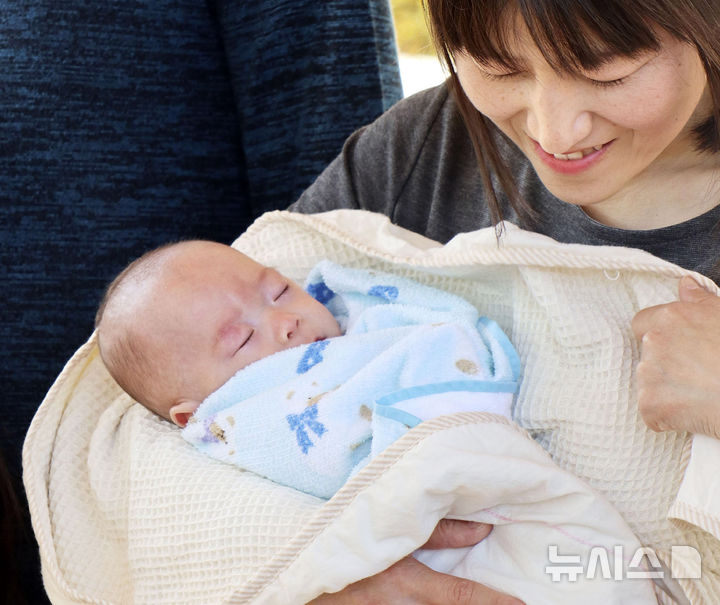 [도쿄=AP·교도/뉴시스]일본 정부가 여성이 출산할 때 드는 비용에 대한 무상화를 추진하고 있다. 저출생 대책의 일환이다. 사진은 2019년 4월 20일 일본 나가노현 아즈미노에 있는 한 병원에서 생후 5개월 된 아기가 엄마에게 안겨있는 모습. 2025.05.15.