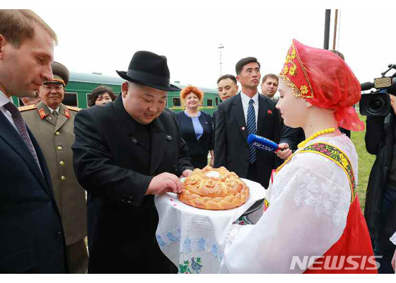 【서울=뉴시스】김정은 북한 국무위원장이 24일 북한-러시아 접경 하산역에 도착해 전통의상을 입은 러시아 여인으로부터 환영의 뜻을 가진 빵과 소금을 받고 있다.(출처=노동신문 캡쳐) 2019.04.25.