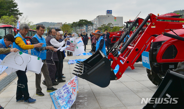 【무안=뉴시스】변재훈 기자 =  6·15공동선언실천 남측위원회 전남본부와 전국농민회 광주·전남연맹이 25일 오전 전남 무안군 삼향읍 전남도청 앞에서 4·27판문점선언 1주년 기념식과 통일트랙터 방북 출정식을 열고 있다. 행사가 끝난 뒤 트랙터 로더로 대북제재와 군사분계선을 상징하는 철조망을 들어올리는 퍼포먼스가 펼쳐지고 있다. 2019.04.25.   wisdom21@newsis.com