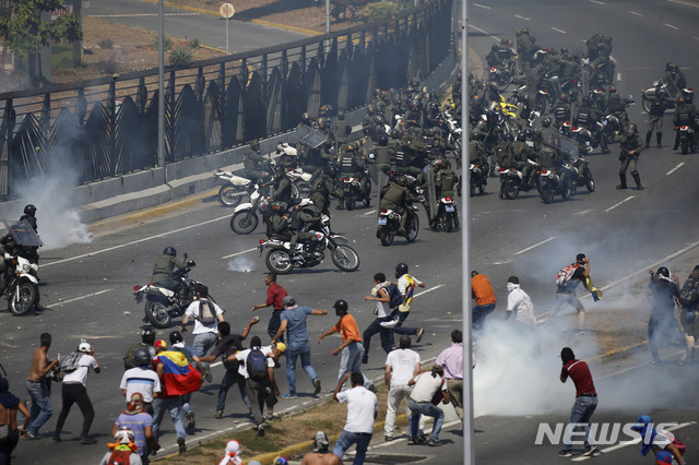 【카라카스=AP/뉴시스】4월30일(현지시간) 베네수엘라 수도 카라카스의 라 카를로타 공군기지 밖에서 반정부 시위대가 최루탄을 쏘는 국가방위군과 대치하고 있다. 베네수엘라 야당 지도자 후안 과이도 국회의장은 이날 야권 정치인 레오폴도 로페즈와 중무장한 소규모 군인들과 함께 “군대 무장봉기로 마두로를 축출하자”라며 거리로 나섰다. 2019.05.01.