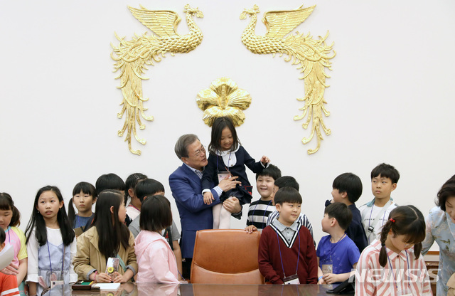 【서울=뉴시스】박진희 기자 = 문재인 대통령이 5일 청와대 본관 집무실에서 제97회 어린이날 청와대 초청행사에 참석한 한 어린이를 대통령 집무실 의자에 앉히고 있다. 2019.05.05.&nbsp; pak7130@newsis.com 
