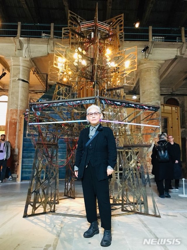 【베니스=뉴시스】박현주 미술전문 기자 = 9일 오후 이탈리아 베니스 옛 조선소터 아르세날레에서 VIP 대상으로 미리 개막한 본전시장에서 이불 작가가 대형 모뉴먼트 ‘오바드 V’ 앞에서 포즈를 취했다.한반도 비무장지대(DMZ) 감시 초소(GP) 철수 과정에서 나온 철조망등 해체 잔해물로 제작된 높이 4m 높이, 철탑같은 작품이다. 질문이 많은 시대, 근대식 건축물같은 작품에는 조명과 모스 부호등의 다양한 신호를 달아 모든 질문에 대한 긍정적인 답을 제시하며 지금 현시대의 흔적을 보여준다. 지난 1999년 제 48 회 베니스 비엔날레 당시 한국관 대표 작가로 참여한 후 20년만에 본전시 작가로 초대된 이불은 명실상부 세계적인 작가로 우뚝섰다. 본 전시에 두 번째 초대되는 영광을 안은최초의 한국 작가로 세계적 명성을 더욱 공고하게 이룬 셈이다. 이번 베니스비엔날레에 이불 작가는 총 3 점의 작품을 선보인다. 오바드 V’외에도 헤이워드 갤러리 회고전에 출품된 바 있는 섬유 조각 <혀의스케일(Scale of Tongue)>을 실크 벨벳 페인팅과 함께 이탈리아 국가관에 설치했다.hyun@newsis.com