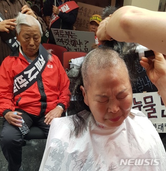 【하남=뉴시스】 문영일 기자 = 국토교부통부 공공주택추진단과 한국토지주택공사(LH) 스마트도시계획처는17일 환경영향평가설명회를 개최하려 했으나 신도시로 지정된 천현·교산동 주민들이 오전 8시30분부터 설명회 장소인 시청 대회의실 입구를 점거해 회의장 입장도 하지 못하고 돌아갔다. 여성 주민이 삭발하고 있다. 2019.05.17. ctdesk@newsis.com