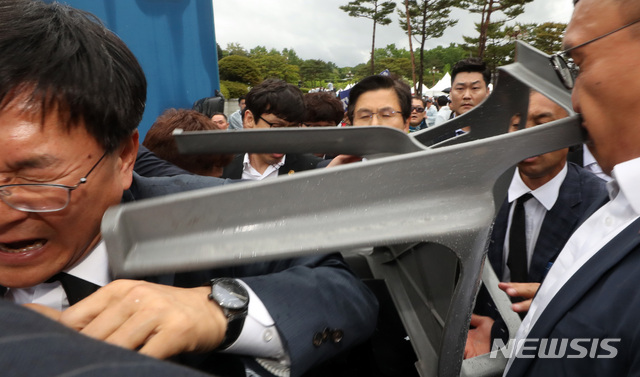 【광주=뉴시스】 박영태 기자 = 자유한국당 황교안 대표가 18일 오전 제39주년 5.18민주화운동 기념식이 열린 광주광역시 북구 국립 5.18민주 묘지 기념식장으로 들어가는 길에 누군가 던진 의자가 날아오고 있다. 2019.05.18.since1999@newsis.com