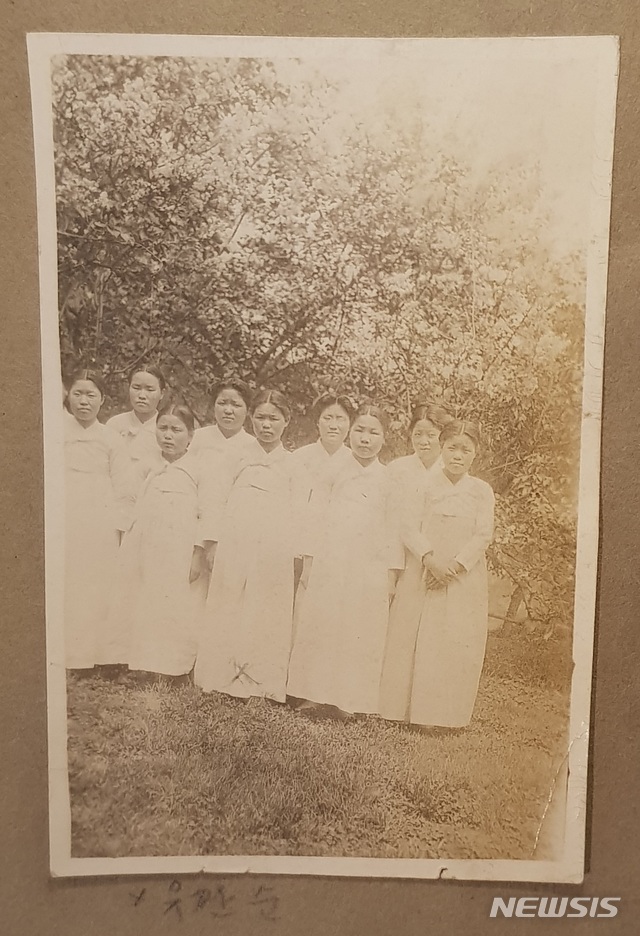 【서울=뉴시스】유관순(가운데)과 학우들이 꽃나무를 배경으로 찍은 사진이다. 1917년~1918년 경에 찍은 것으로 추정된다. 유관순과 같은 열의 오른편에 있는 이가 김복희 열사다. 이 사진은 이화학당 창설시기 앨범 'Ewha in the past'에 수록돼있다. (사진 = 이화여자대학교 이화역사관 제공)