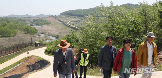 [철원=뉴시스]사진공동취재단 = 2019년 5월 22일 시민들이 강원도 철원군 'DMZ 평화의 길'을 걷고 있다. 시민들의 뒷편으로 보이는 철책선 너머 비무장지대를 역곡천이 가로질러 흐르고 있다. 2026.02.12. photo@newsis.com