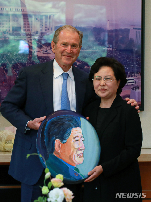 【서울=뉴시스】23일 경남 진해 봉하마을 노무현 전 대통령 사저에서 조지 부시 전 미국 대통령이 직접 그린 노무현 전 대통령 초상화를 권양숙 여사에게 선물하고 있다. 2019.05.23. (사진=노무현재단 제공) photo@newsis.com