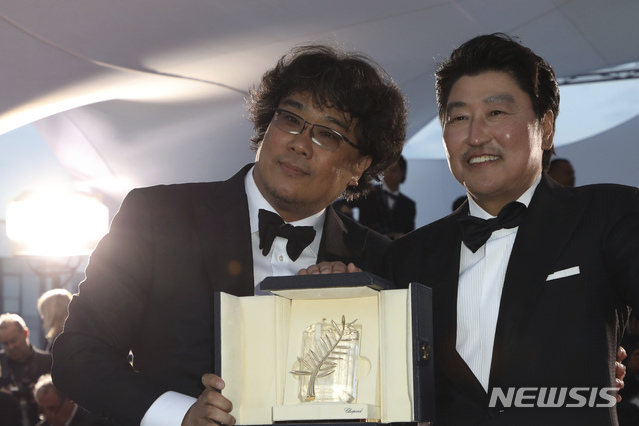 【칸=AP/뉴시스】봉준호(왼쪽) 감독이 5월25일(현지시간) 프랑스 칸에서 열린 제72회 칸 국제영화제시상식에서 영화 '기생충'으로 '황금종려상'을 받고 배우 송강호와 함께 포즈를 취하고 있다. 한국 영화가 칸영화제 최고 상인 황금종려상을 받은 것은 사상 처음으로 봉준호 감독은 "함께한 위대한 배우들이 없었다면 한 장면도 찍을 수 없었을 것"이라고 배우들에게 고마움을 전했다. 봉 감독은 '괴물'(2006, 감독주간) '도쿄!'(2008, 주목할 만한 시선) '마더'(2009, 주목할 만한 시선) '옥자'(2017, 경쟁)에 이어 5번째로 칸에 입성해 상을 받았다. 2019.05.26.