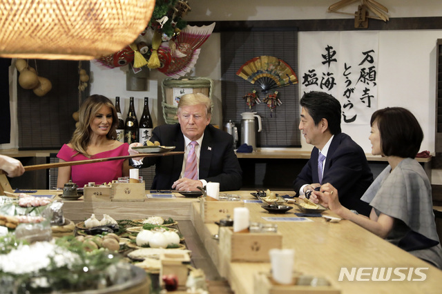 U.S. President Donald Trump, second left, is served a baked potato with butter while sitting at a counter with first lady Melania Trump, second left, Japan's Prime Minister Shinzo Abe, second right, and his wife Akie Abe during a dinner at the Inakaya restaurant in the Roppongi district of Tokyo, Sunday, May 26, 2019. (Kiyoshi Ota/Pool Photo via AP)