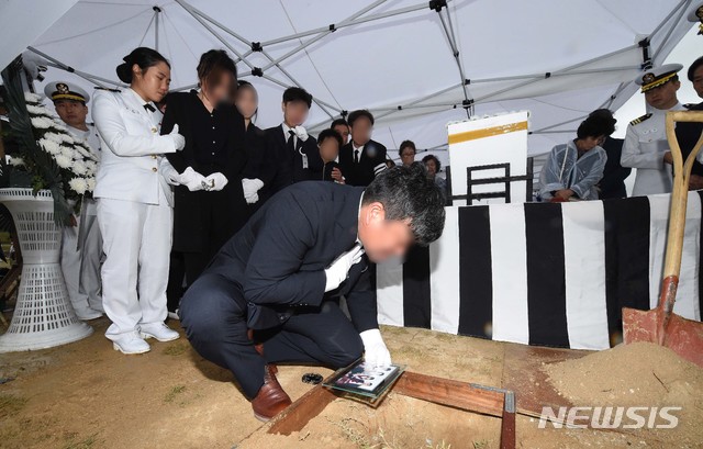 【대전=뉴시스】 함형서 기자 =청해부대 최영함 입항 행사 도중 홋줄(선박 육지 고정용 밧줄)이 끊어지는 사고로 순직한 고(故) 최종근 하사의 안장식이 27일 오후 대전 유성구 국립대전현충원에서 열려 아버지가 가족사진을 넣고 있다. 2019.05.27.foodwork23@newsis.com